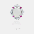 Silver-tone ring with an oval white cabochon framed by clear pear-cut stones and small pink accents