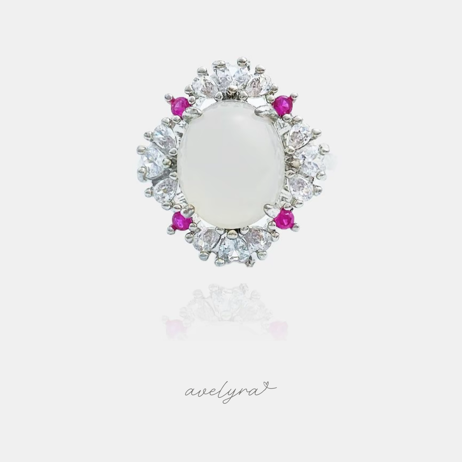 Silver-tone ring with an oval white cabochon framed by clear pear-cut stones and small pink accents