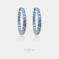 Silver-tone inside-out hoop earrings set with a continuous row of round light-blue crystals.