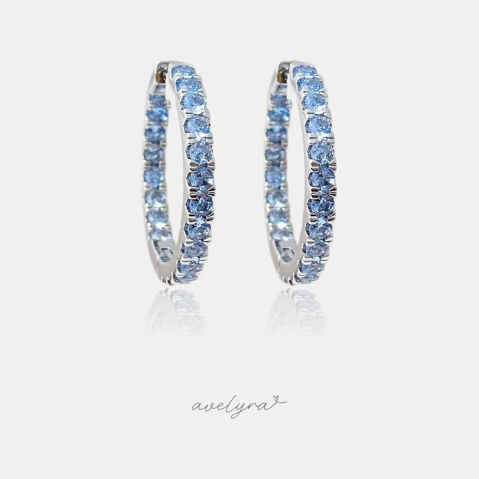 Silver-tone inside-out hoop earrings set with a continuous row of round light-blue crystals.