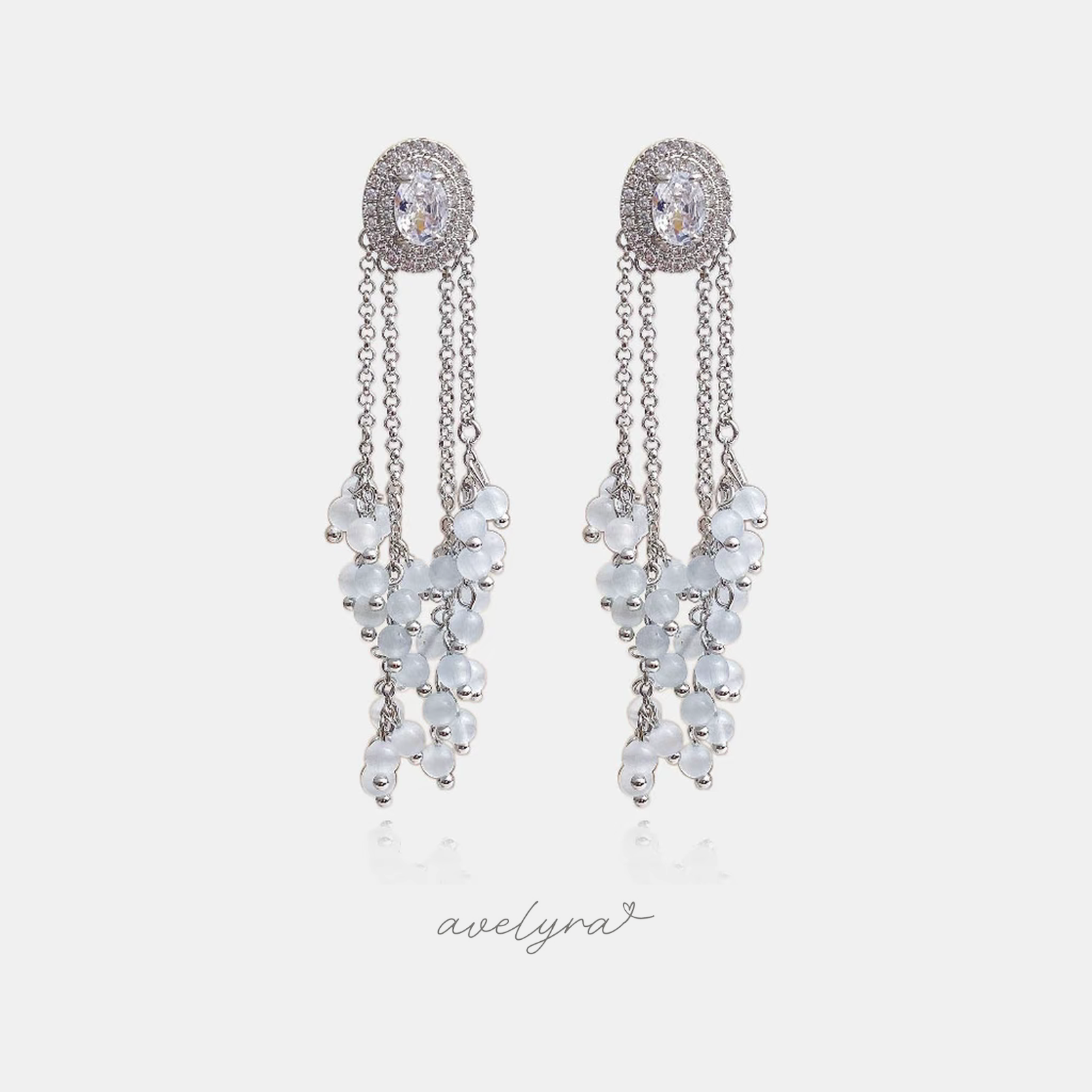 Silver-tone earrings with an oval crystal halo top and dangling clusters of frosted white round beads.