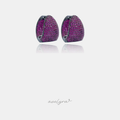 Chunky huggie hoop earrings fully paved with vivid fuchsia pink stones in a dark-tone setting.