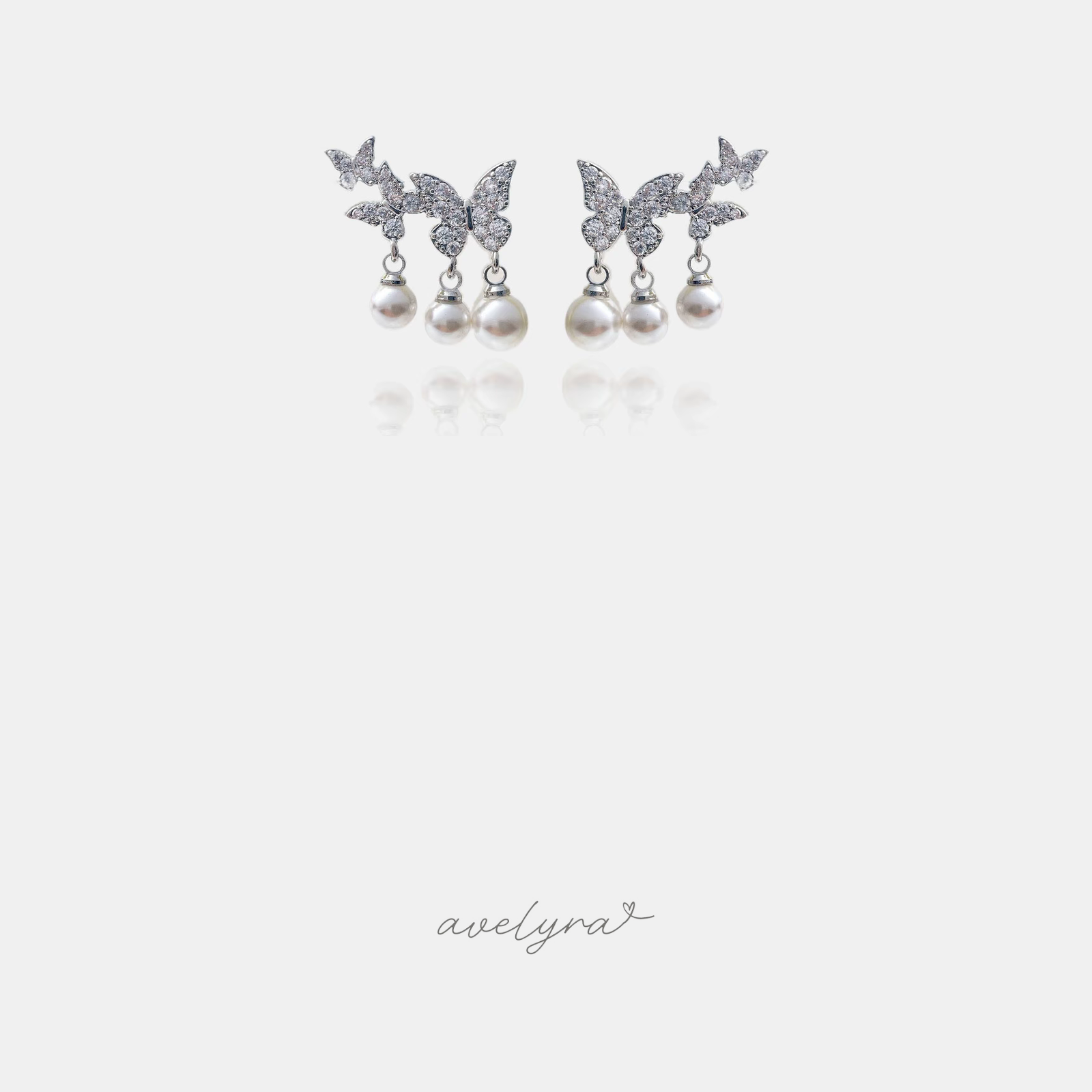 Silver-tone earrings with pave butterflies and three small white pearl drops each.