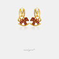 Gold-tone huggie earrings with a red enamel rocking-horse charm.