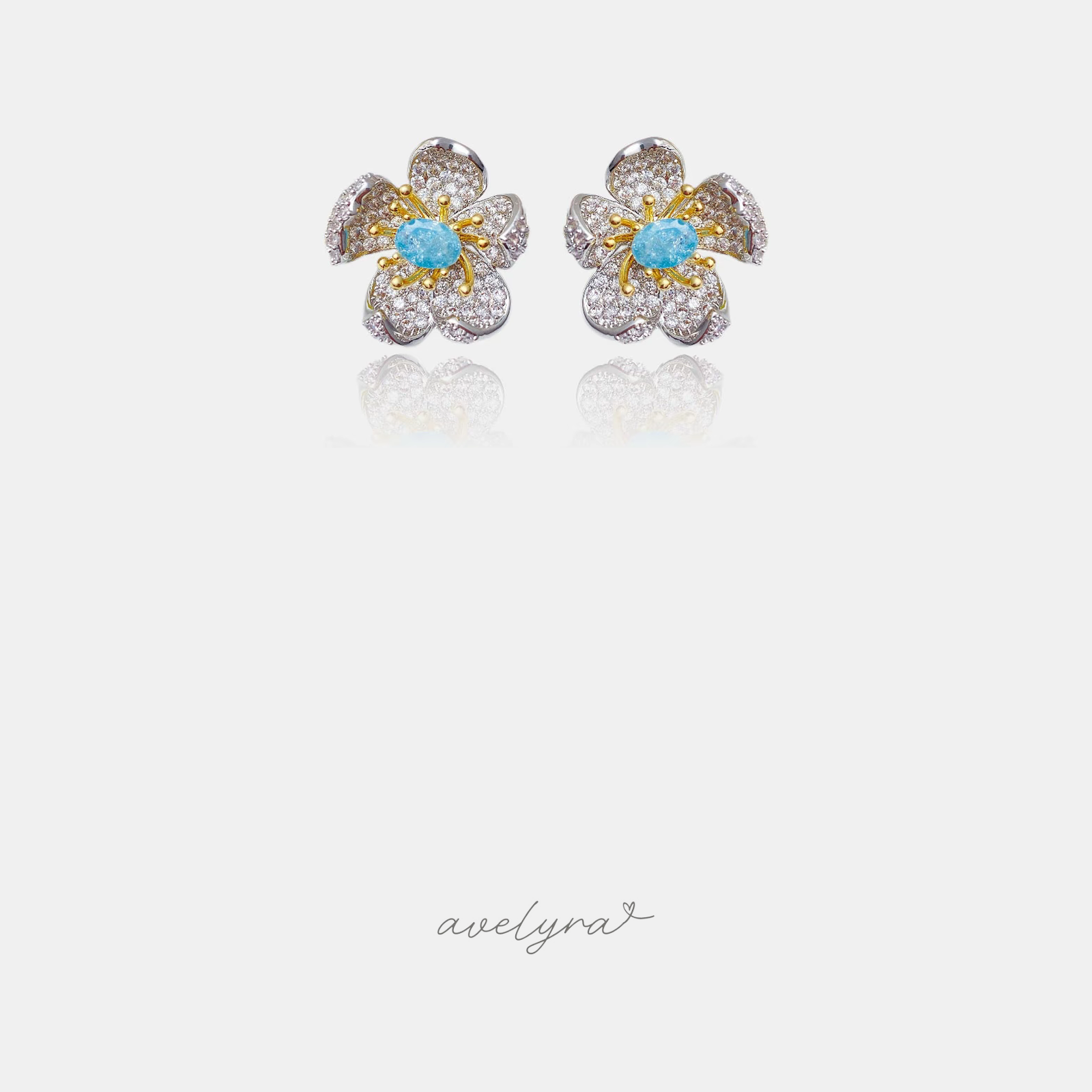 Floral stud earrings with pave white petals, golden stamens and a light blue center stone.