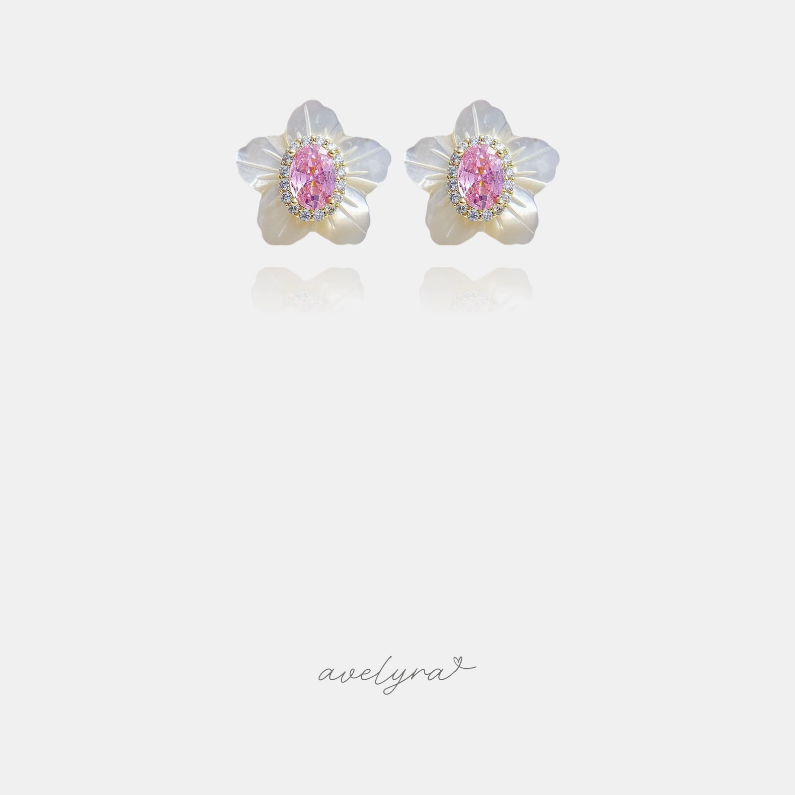 White carved flower stud earrings with a pink oval stone and clear halo in the centre.