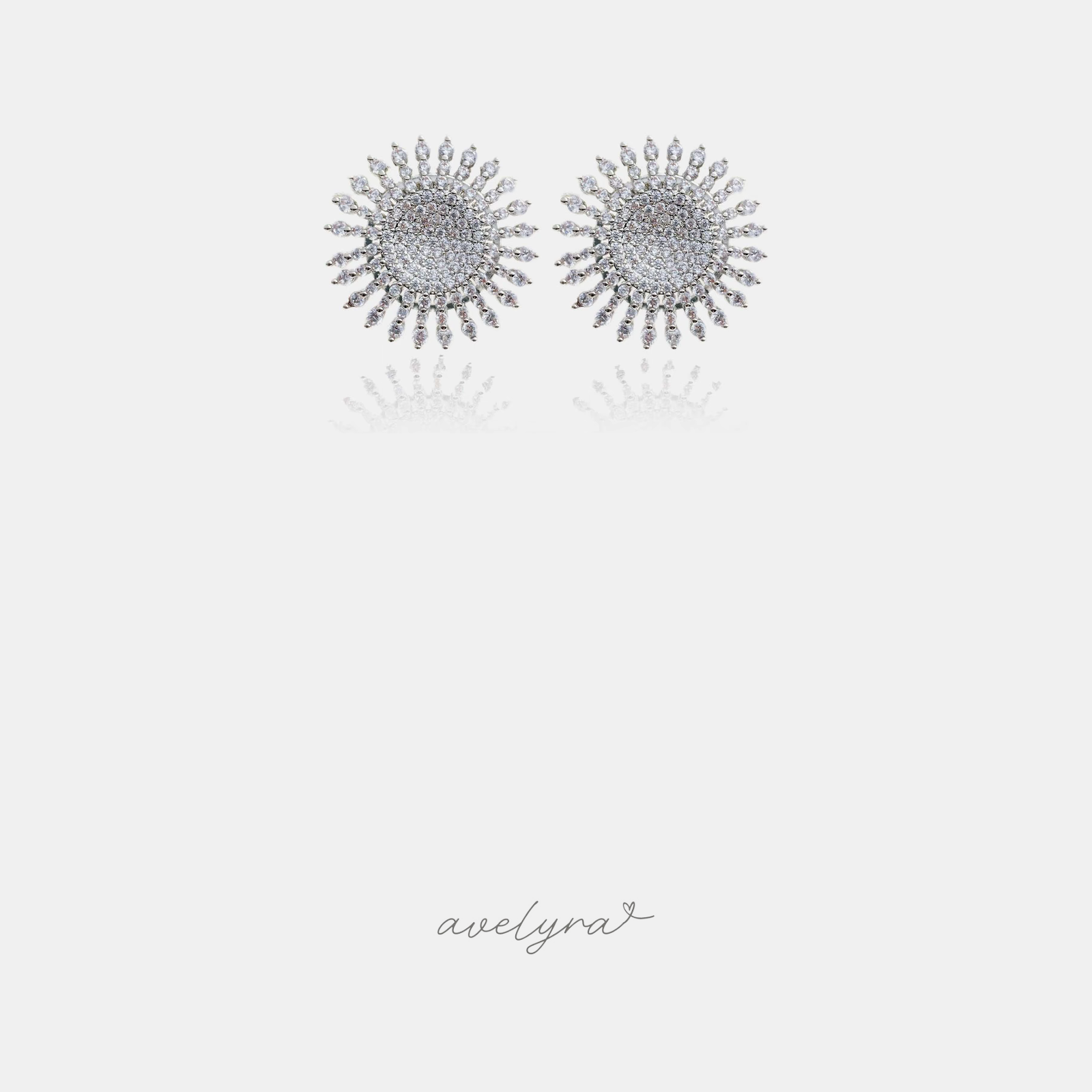 Pair of silver-tone sunburst stud earrings with pave clear stones and radiating spokes of small stones.