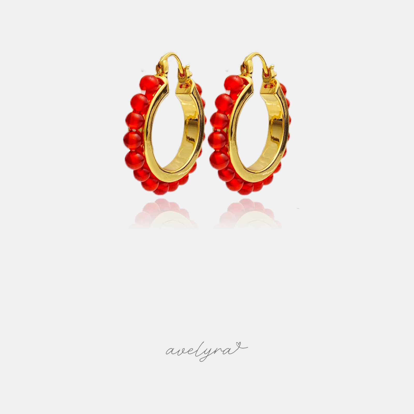 Gold-tone hoop earrings edged with a row of glossy red round beads.