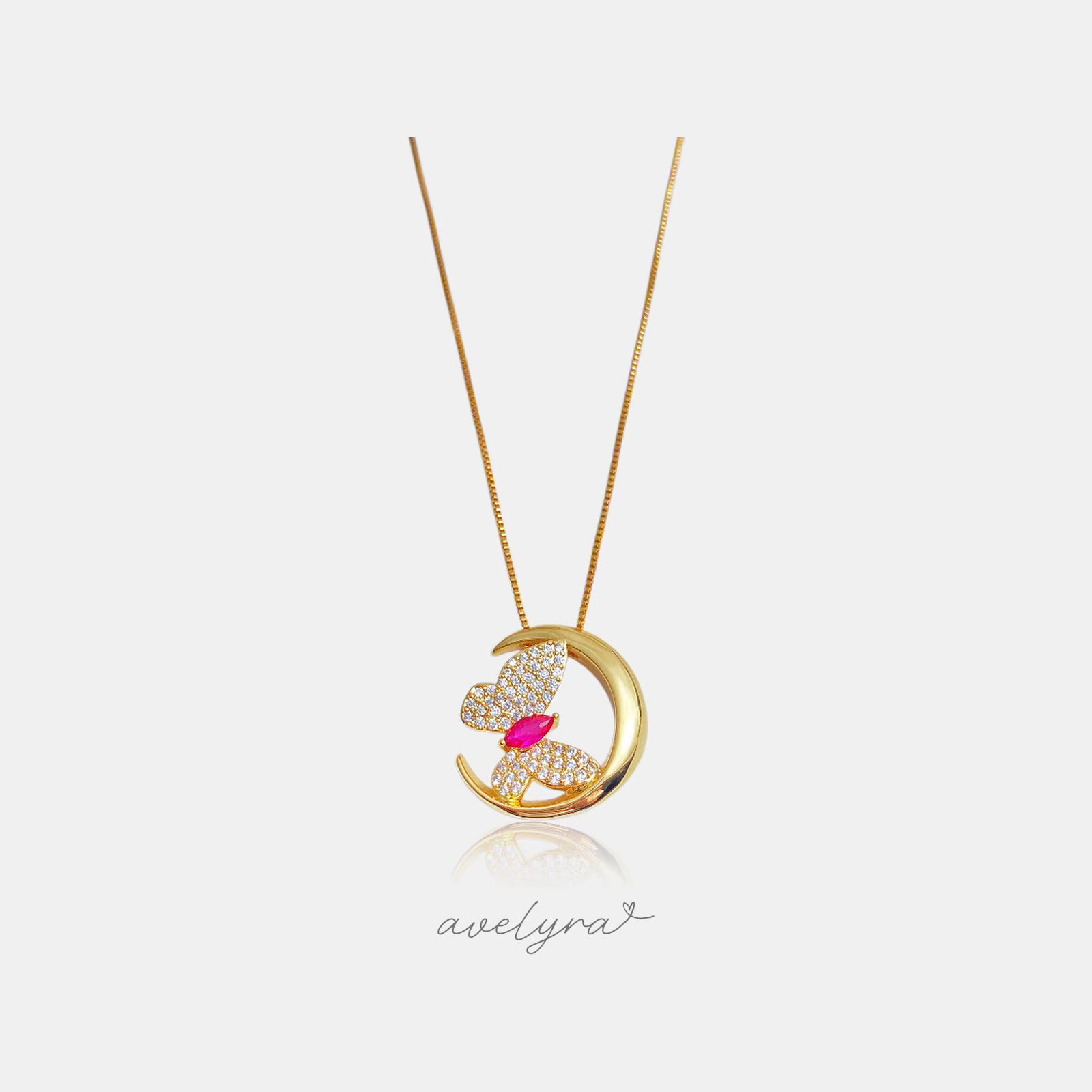 Gold crescent moon pendant with a pave butterfly and pink marquise stone on a thin chain.