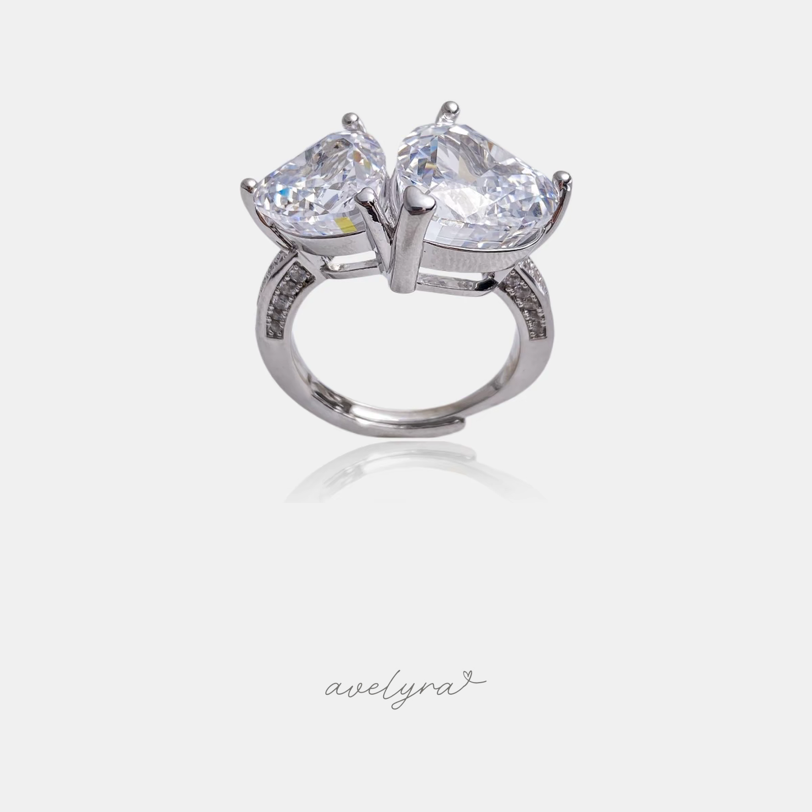 Silver-tone ring with two clear heart-cut crystals side by side on a pave band