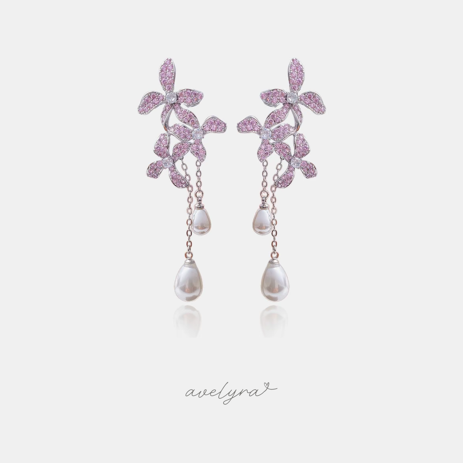 Silver-tone earrings with pink pave crystal flowers and two chains ending in white teardrop pearls.
