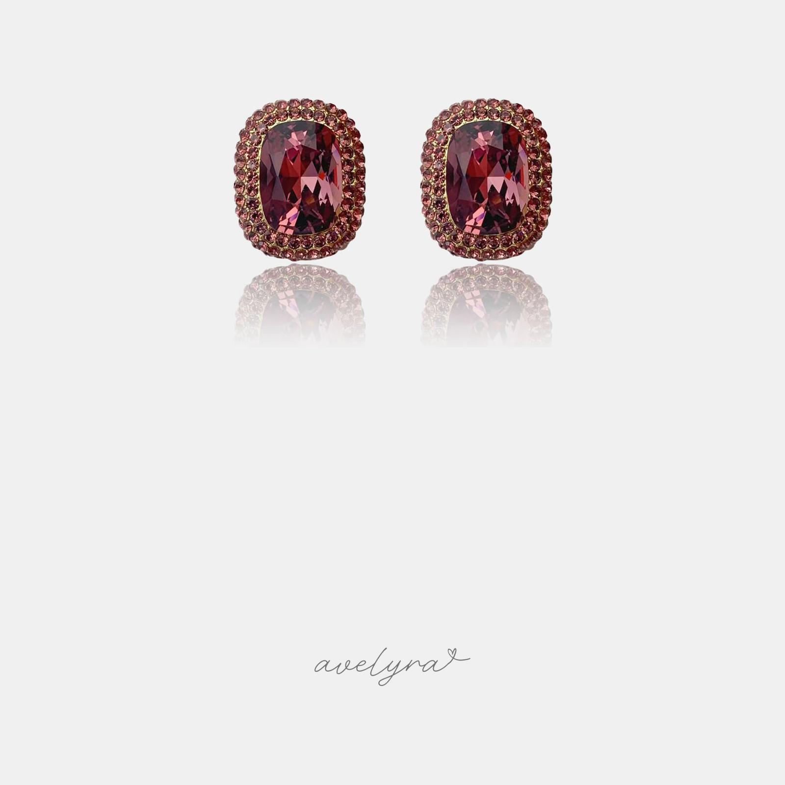 Cushion-shaped deep red crystal stud earrings surrounded by a double halo of small red stones.