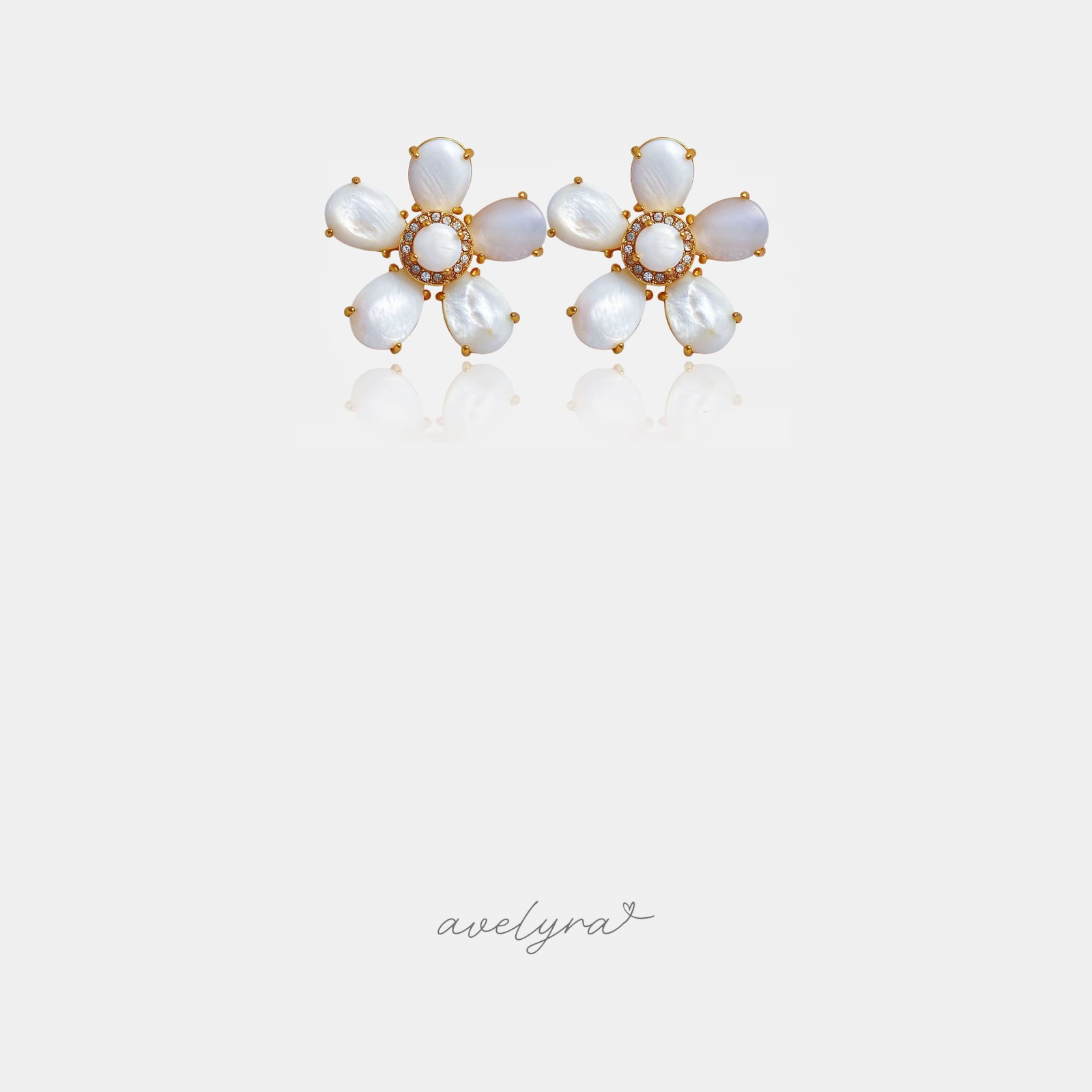 White shell-petal flower stud earrings with a gold-tone crystal centre.