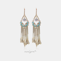 Gold-tone chandelier earrings with a pear-shaped clear crystal, small aqua-blue beads and chain fringe ending in champagne baguette drops.