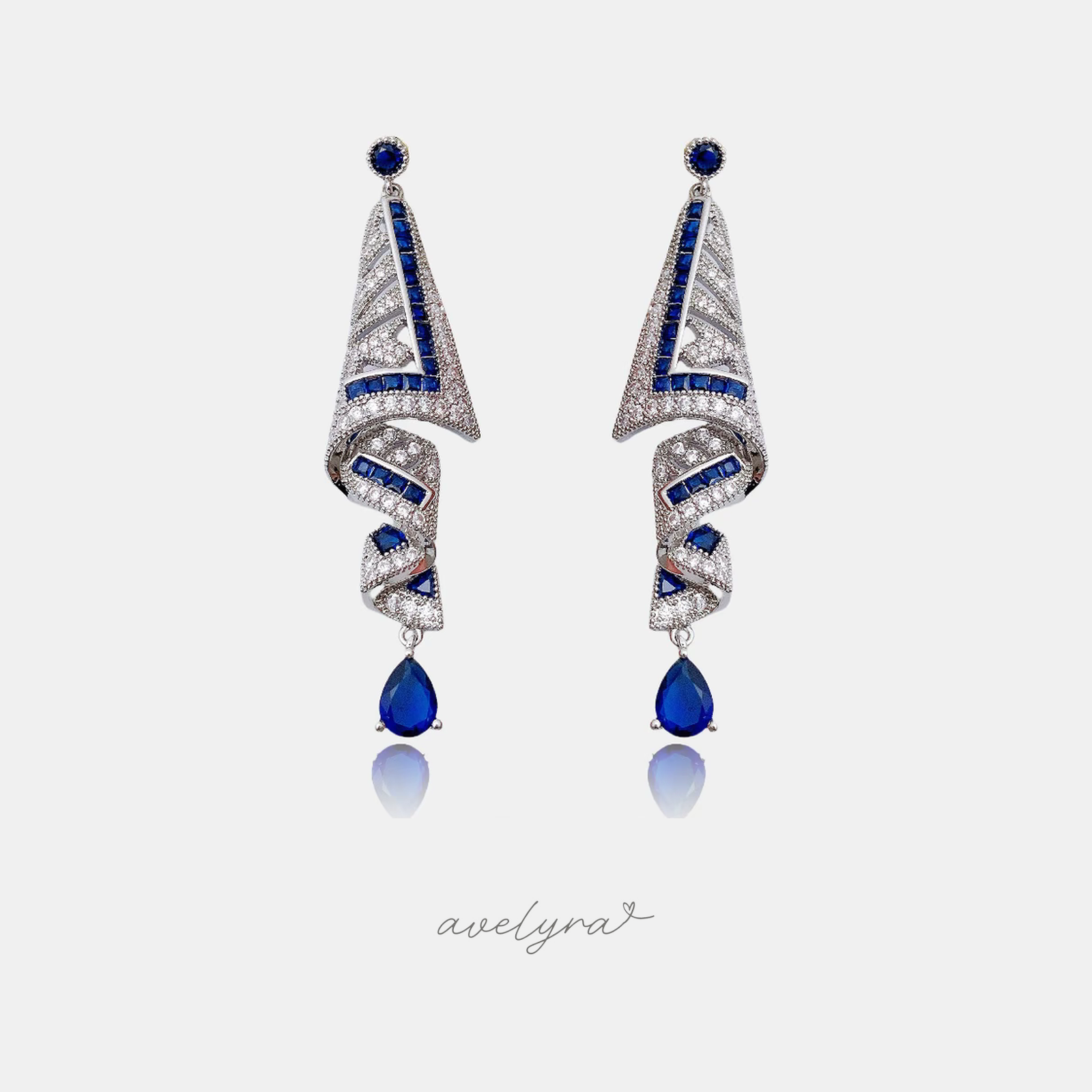 Silver-tone drop earrings with a geometric art-deco design of blue baguette stones and clear crystals ending in a blue pear-shaped stone.