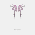 Silver-tone bow earrings covered in pink crystals with a central pink stone and long ribbon-like dangles.