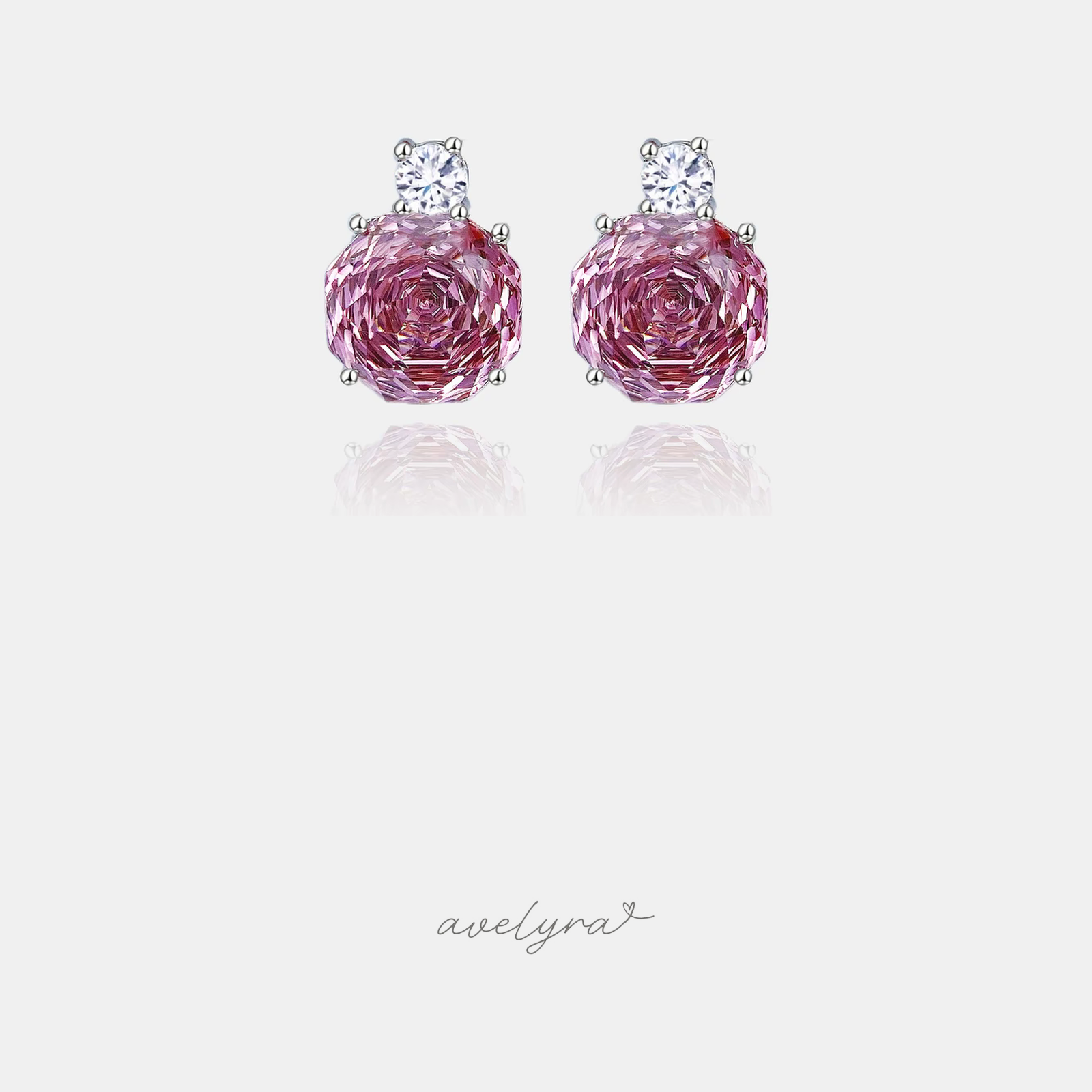 Silver-tone stud earrings with a large pink rose-cut stone below a small clear round crystal.