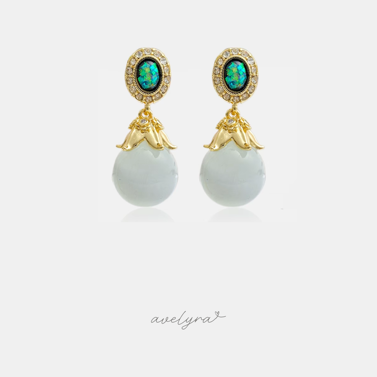 Gold-tone drop earrings with iridescent green-blue oval tops and pale round bead drops.