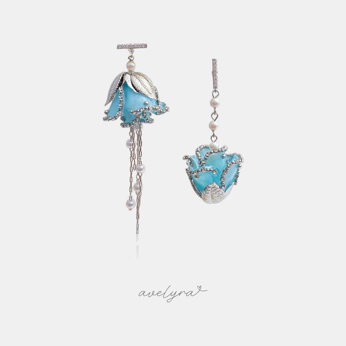 Asymmetric blue flower earrings, one with pearl-dotted chain tassels and one cupped in silver leaves.