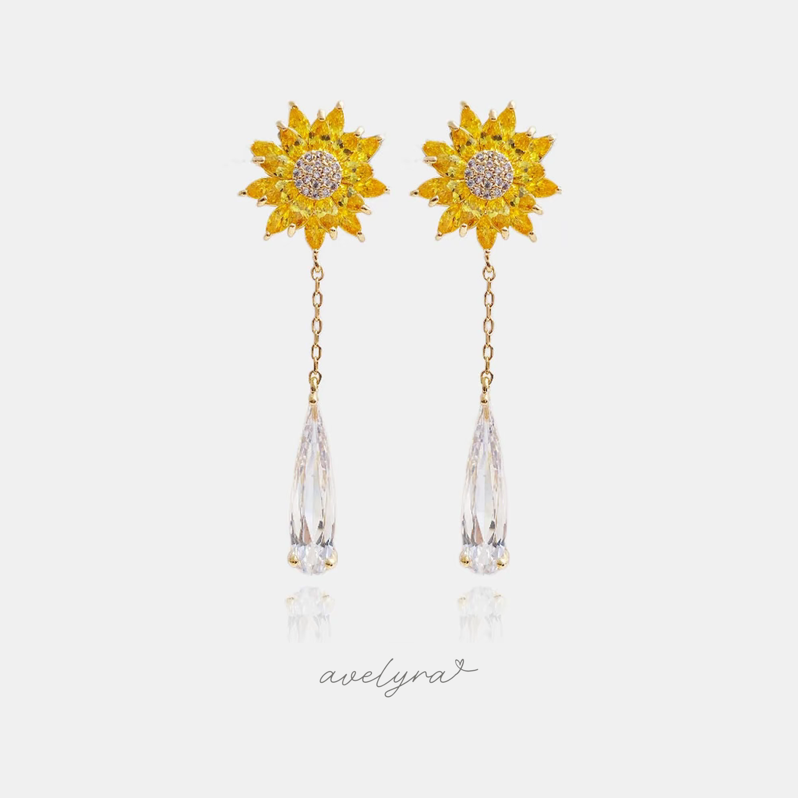 Gold-tone earrings with a yellow sunflower and a long clear faceted teardrop on a chain.