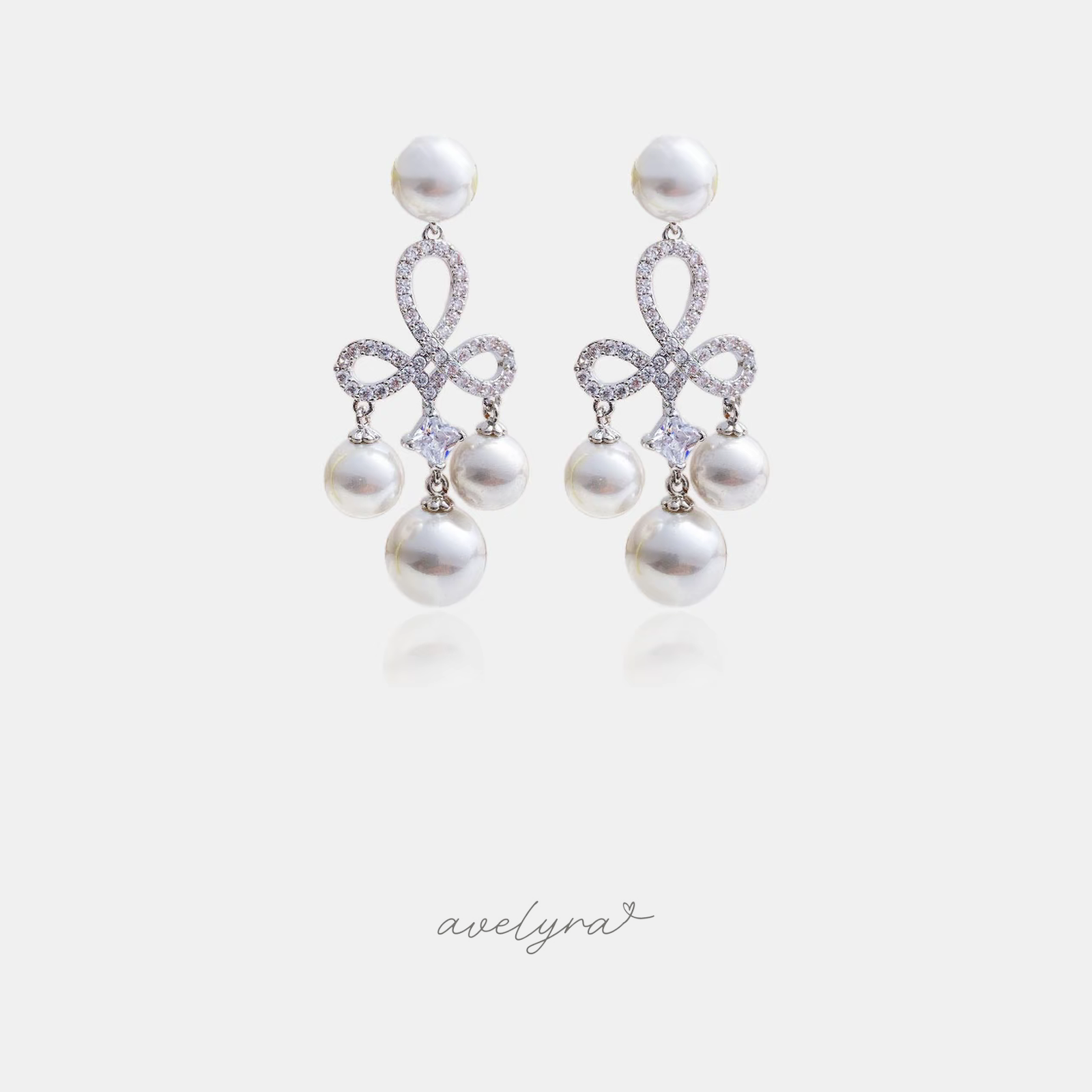 Silver-tone chandelier earrings with a pave bow and a cluster of white pearls.