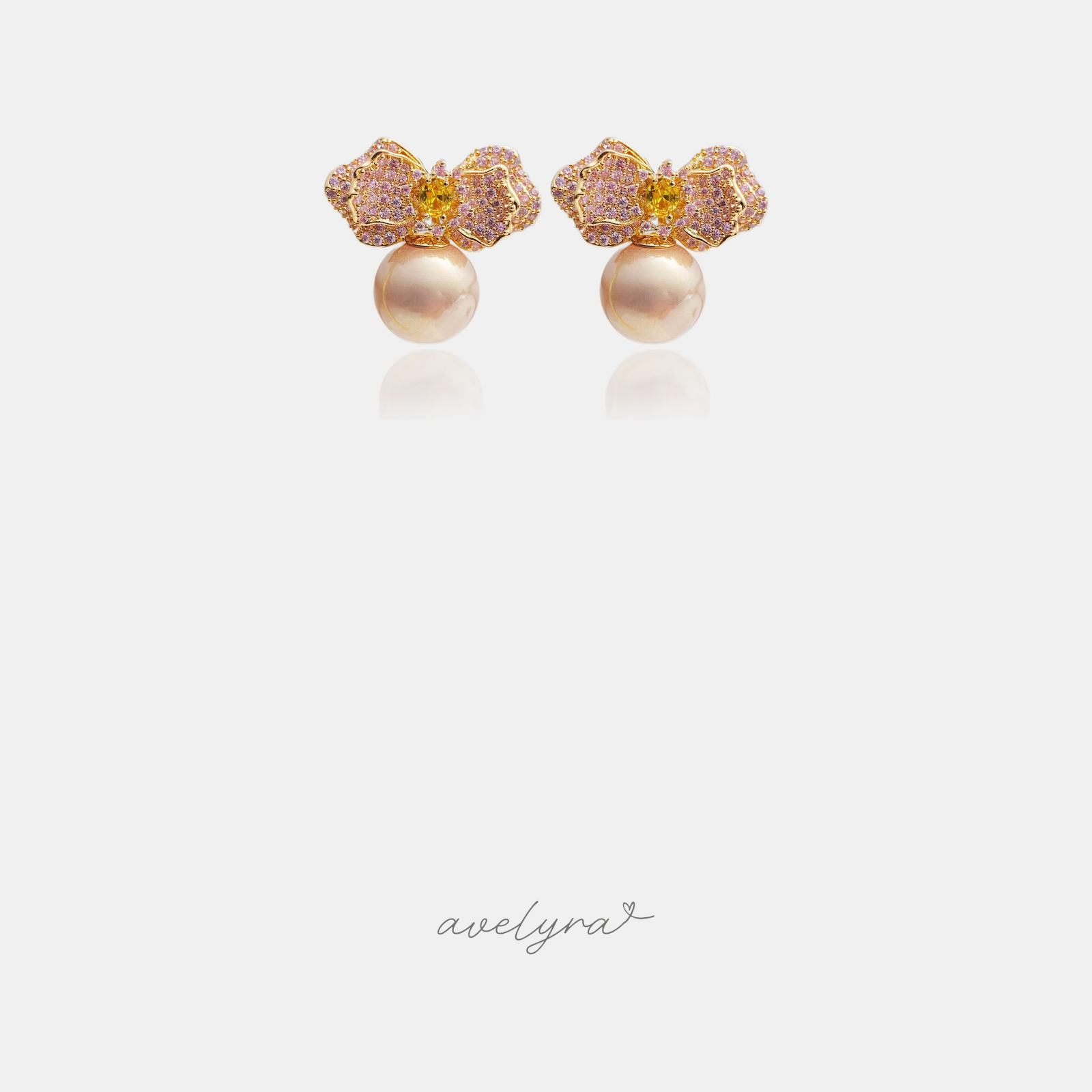 Pink pavé flower earrings with a golden centre stone above a rounded pearl.