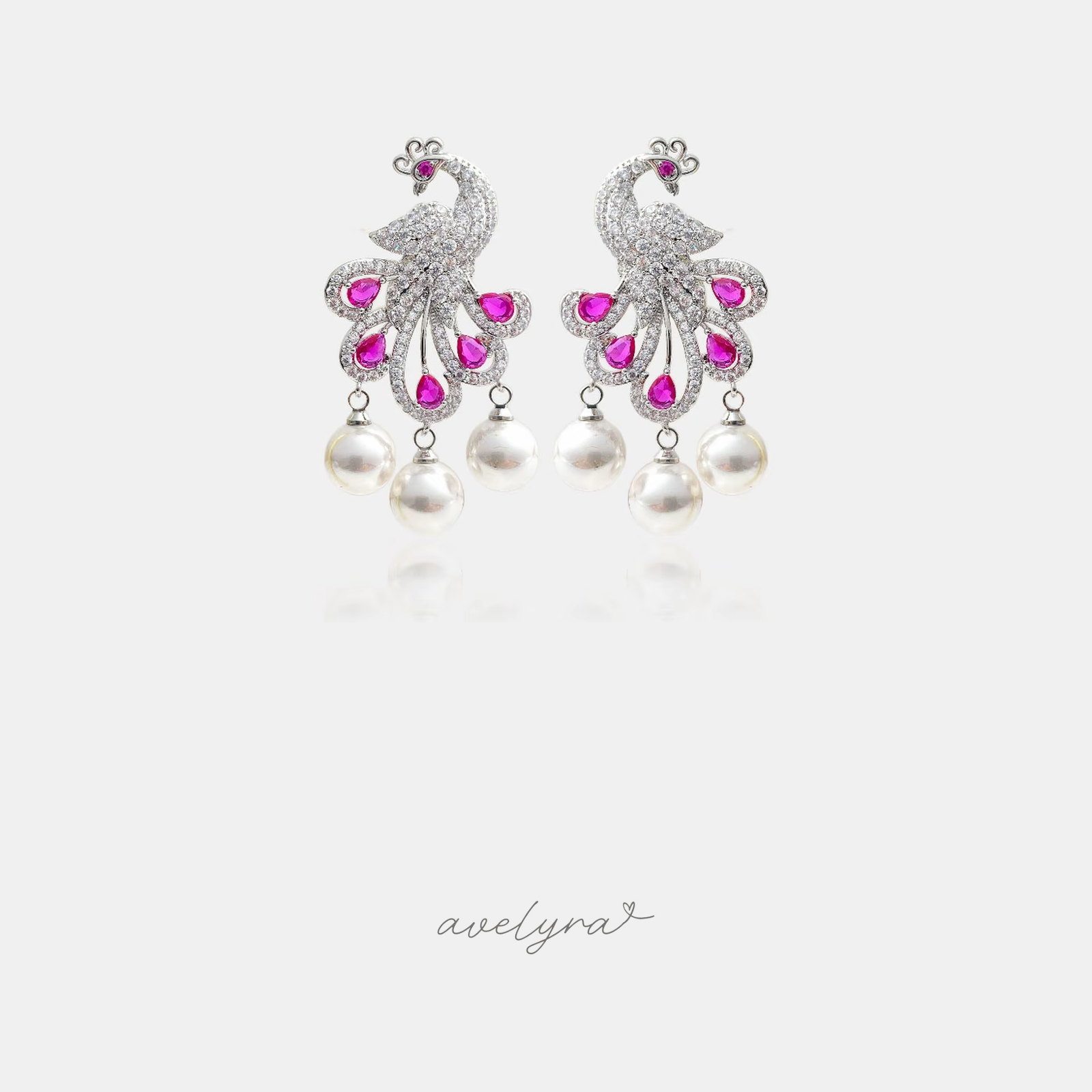 Silver-tone peacock chandelier earrings with clear crystal plumage, magenta stones and three pearl drops.