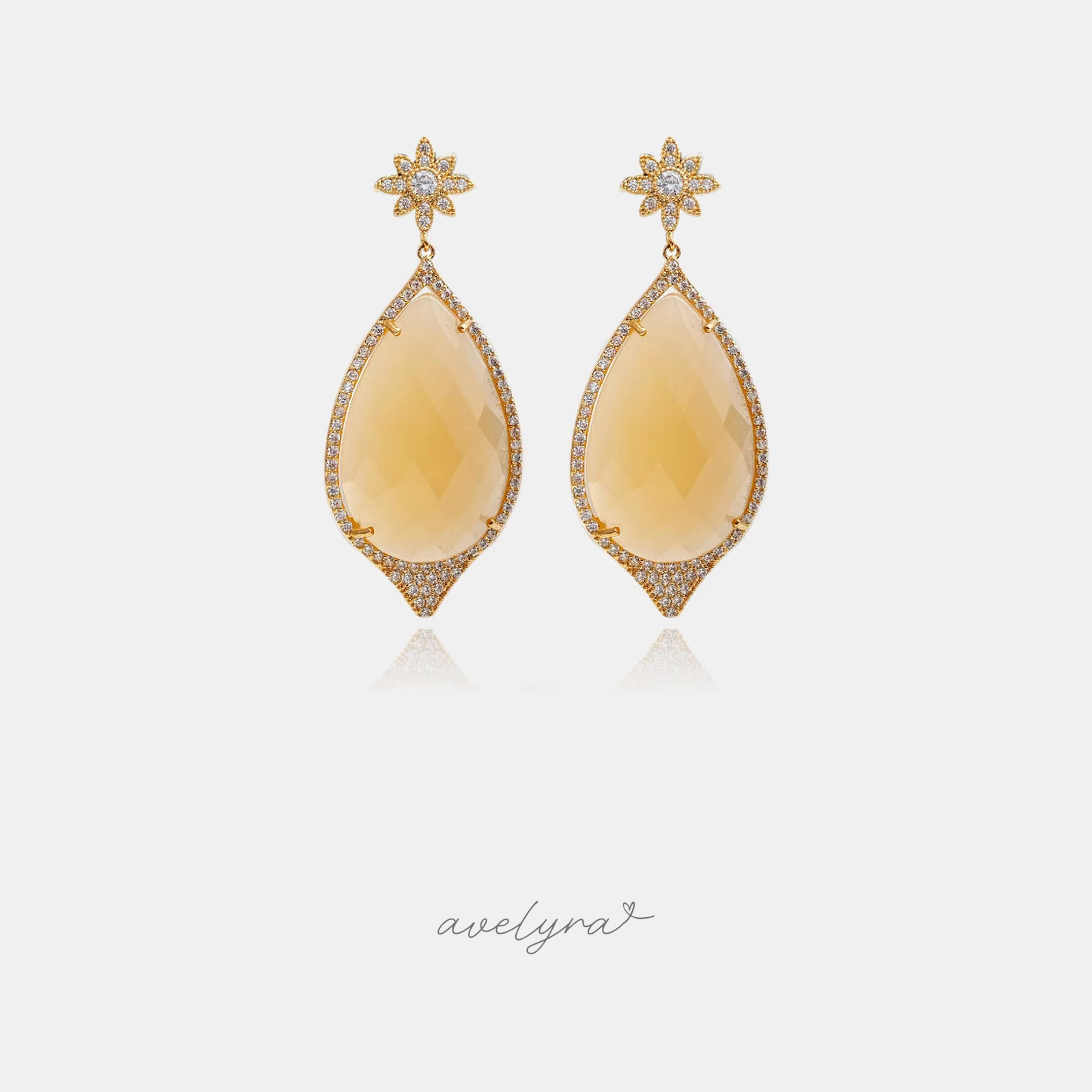 Gold-tone drop earrings with crystal star stud and large honey-yellow teardrop stone in a pave halo.