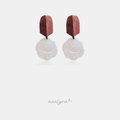 Dangle earrings with brown wooden top and carved white rose-shaped drop on a dark cord.