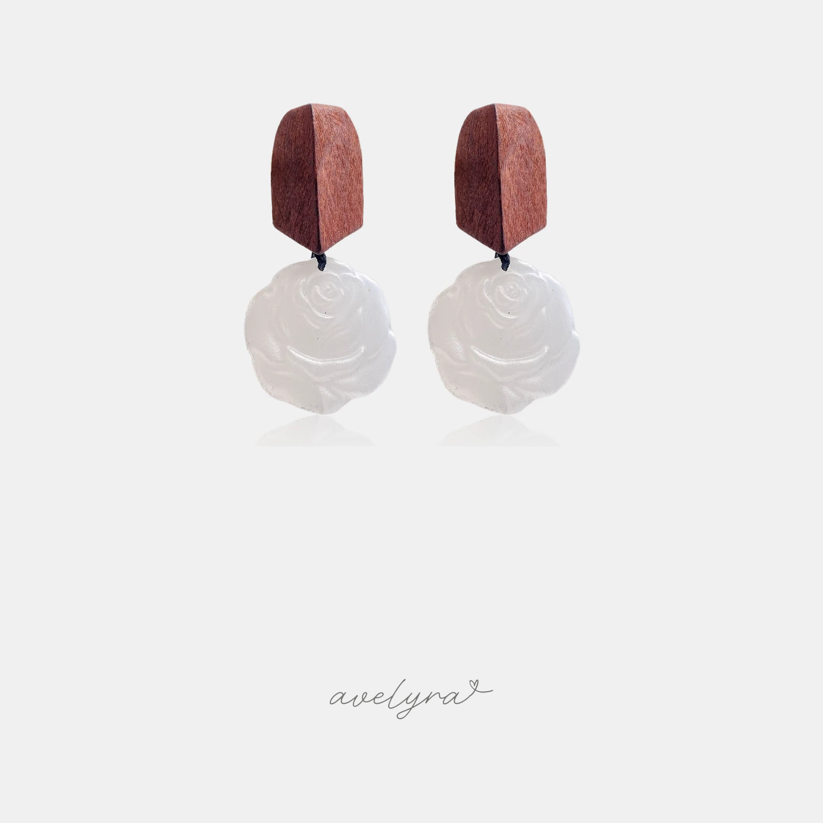 Dangle earrings with brown wooden top and carved white rose-shaped drop on a dark cord.