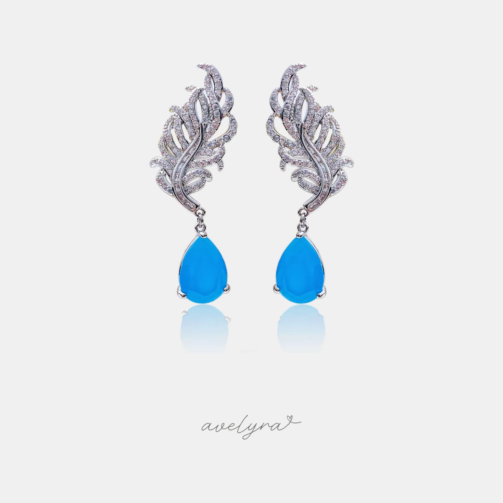 Silver-tone feather-shaped drop earrings with a blue teardrop stone.