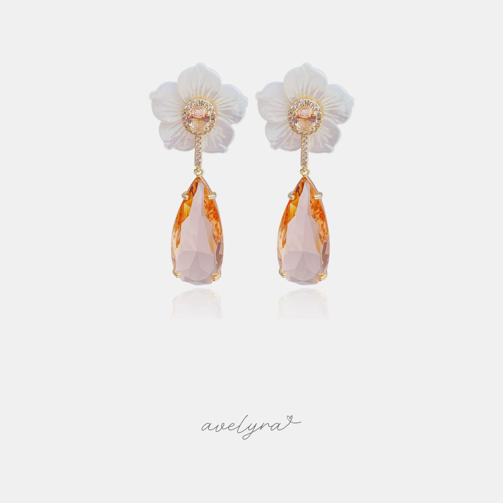 White carved flower stud earrings with a faceted peach teardrop drop.