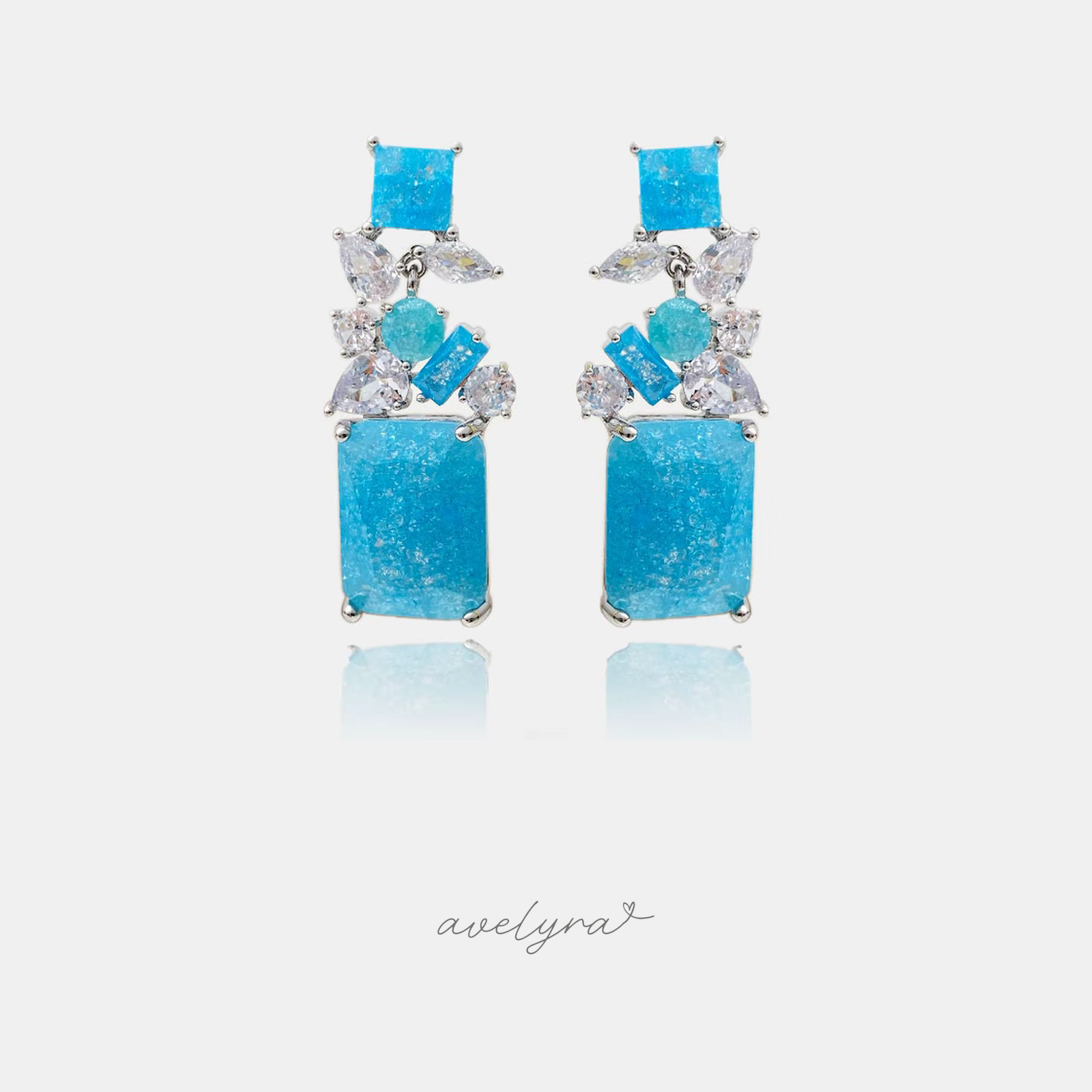 Silver-tone dangle earrings with clustered blue and clear stones and a large aqua drop.