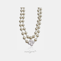 Two-strand cream pearl necklace with a silver clover pendant of clustered clear stones.