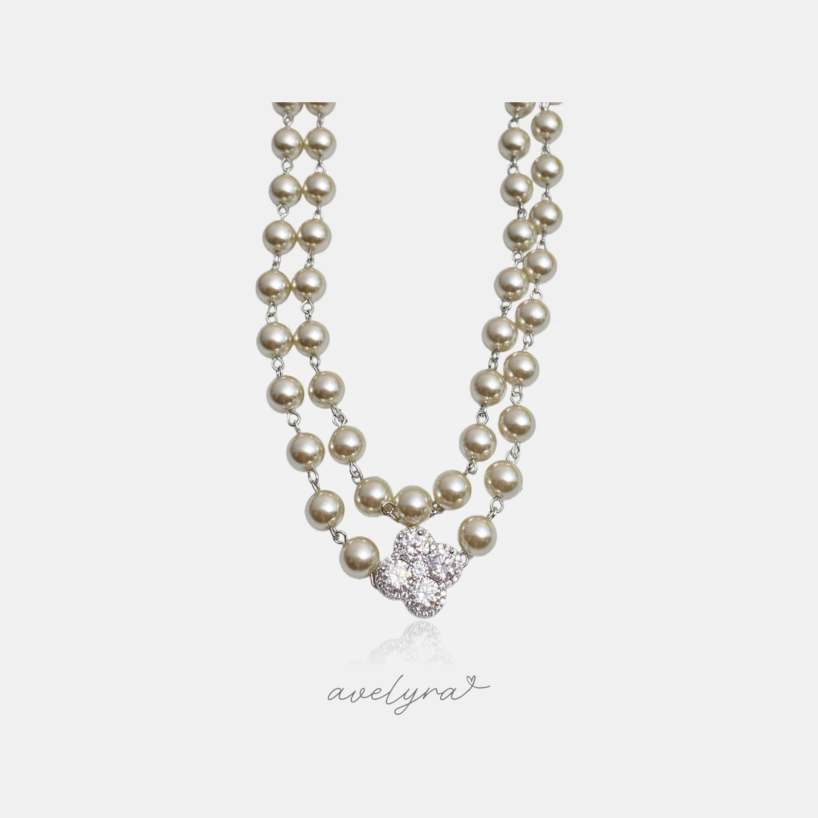 Two-strand cream pearl necklace with a silver clover pendant of clustered clear stones.