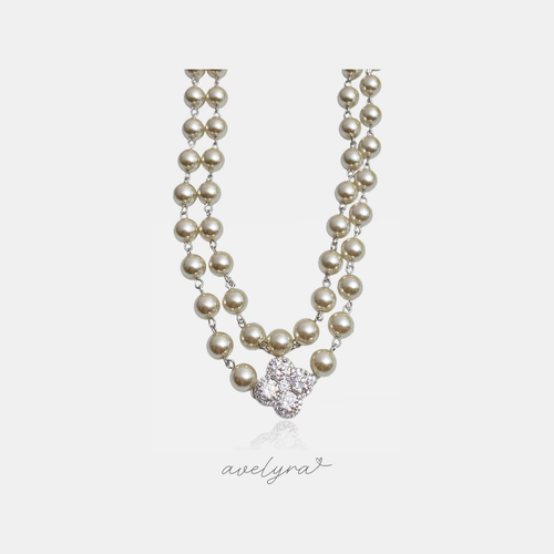 Two-strand cream pearl necklace with a silver clover pendant of clustered clear stones.