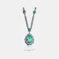 Silver chain necklace with crystal-framed blue-green teardrop stones and a large iridescent teardrop pendant edged with pale-blue cabochon petals in a crystal halo.