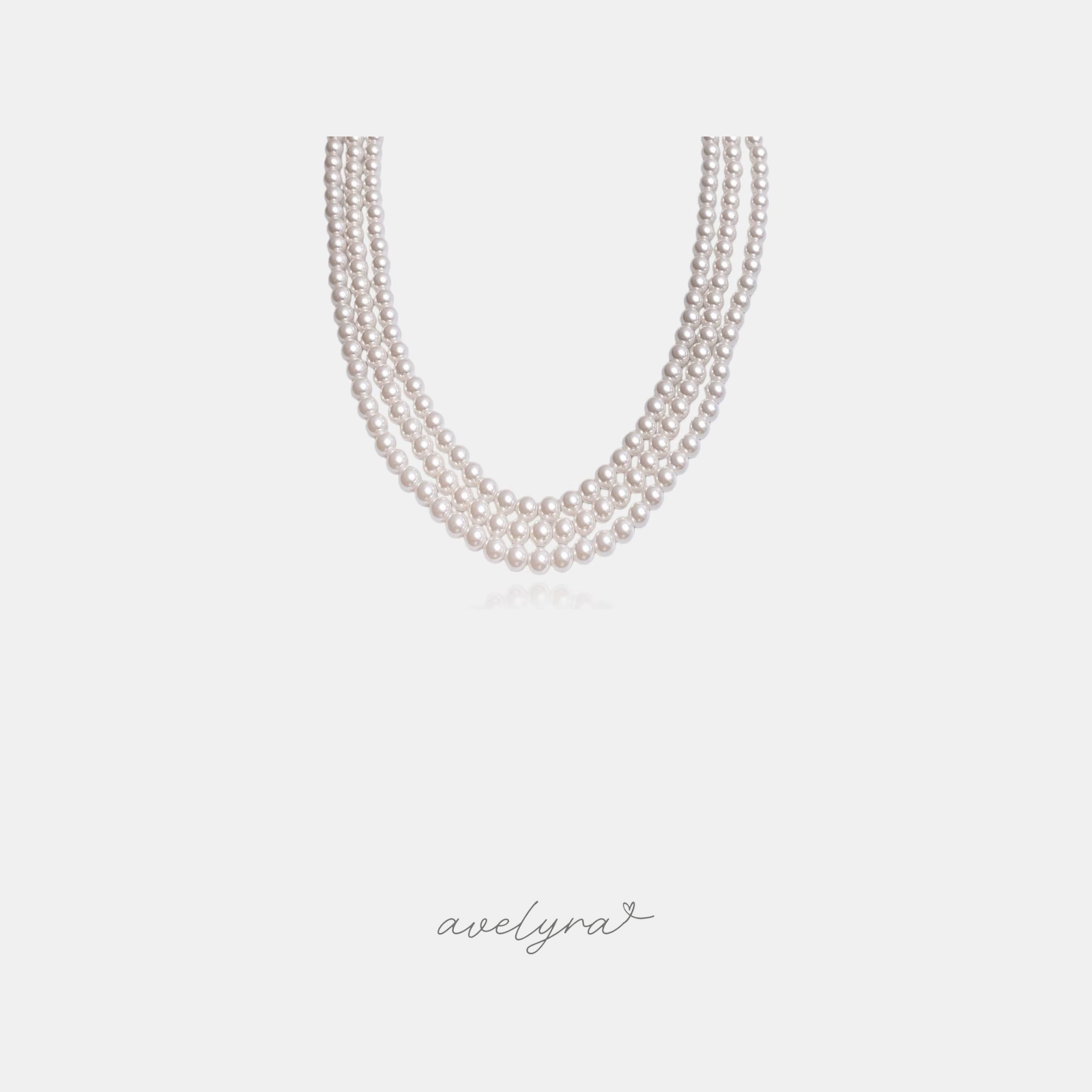 Three-strand necklace of round white pearls.