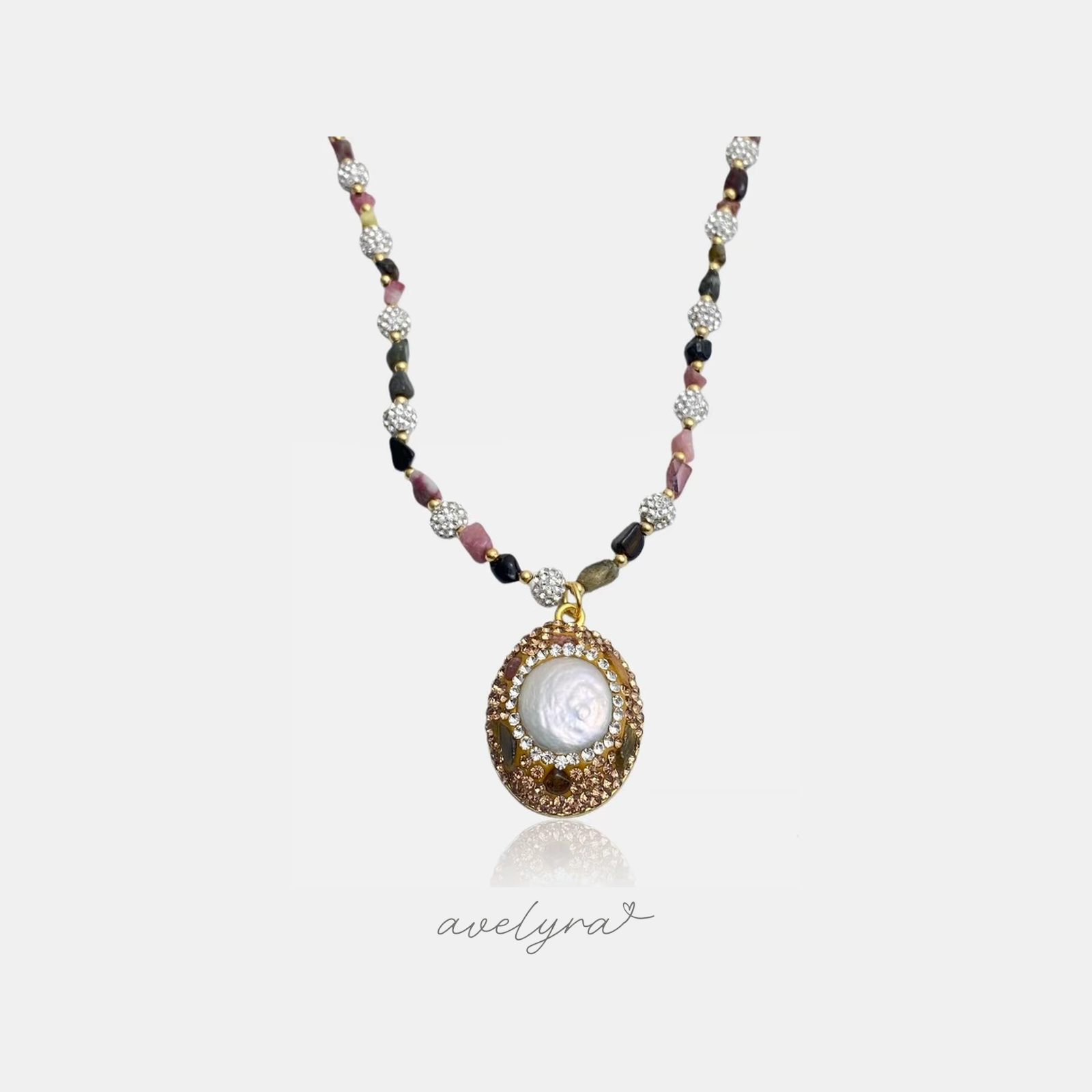 Golden crystal-framed pearl medallion pendant on a strand of pink and dark stone beads with pave beads.
