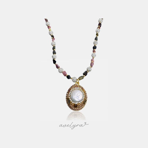 Golden crystal-framed pearl medallion pendant on a strand of pink and dark stone beads with pave beads.