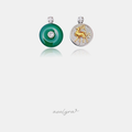 Green round disc pendant with crystal flower centre beside a pave circle pendant with a golden stag motif.