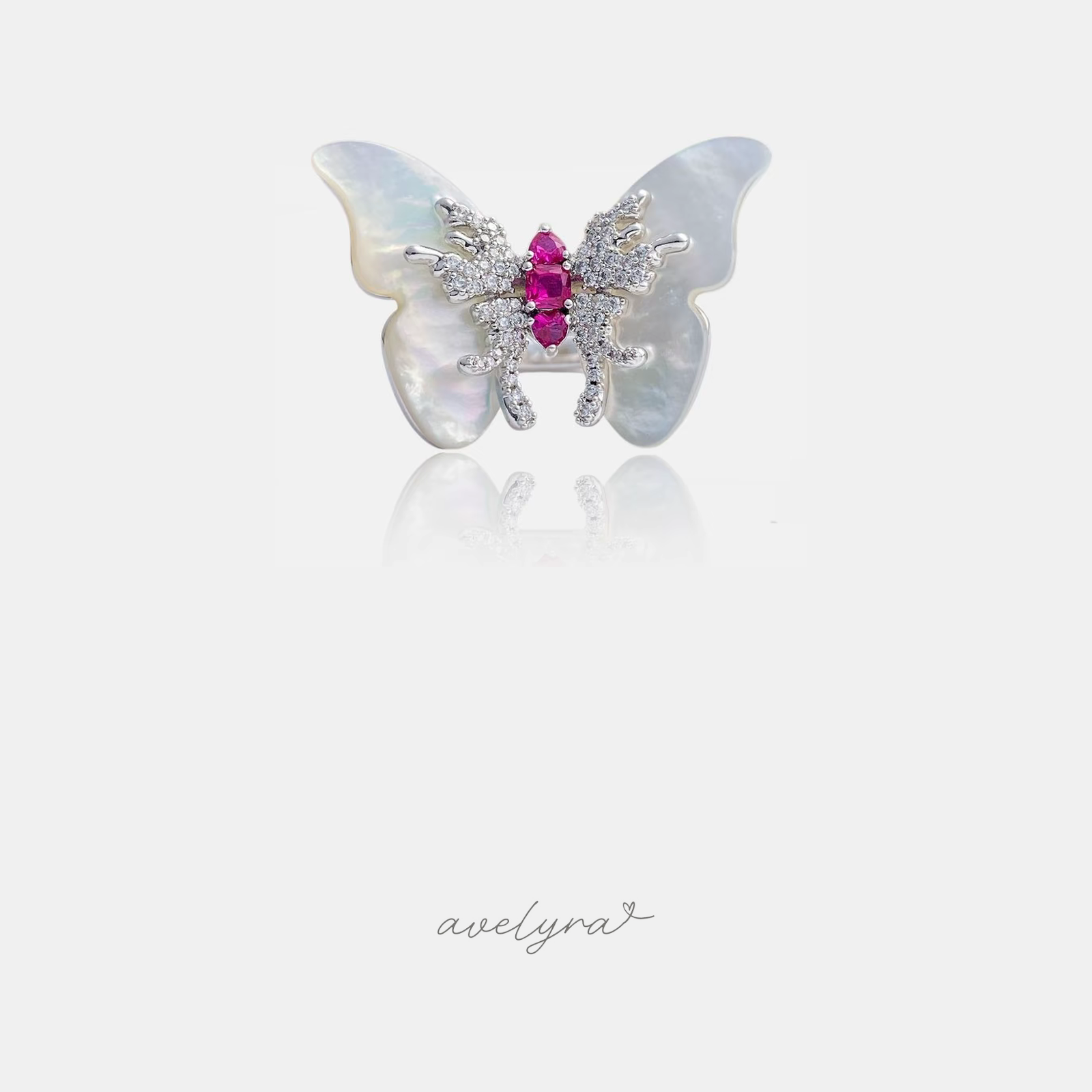 Ring shaped as a butterfly with iridescent shell wings, pave-set body and pink centre stones