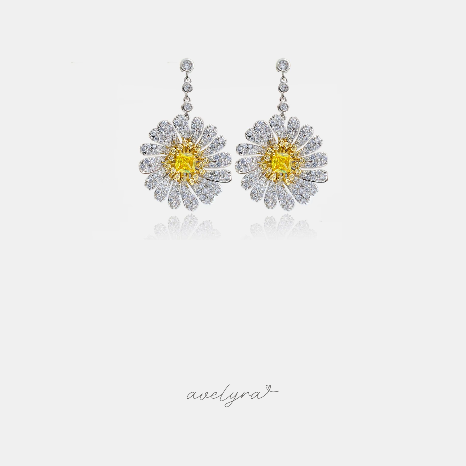 Drop earrings with a daisy flower of clear crystal petals surrounding a square golden-yellow crystal center, hung from two bezel-set crystals.