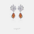 Silver-tone crystal filigree dangle earrings with amber-orange marquise stone drops.