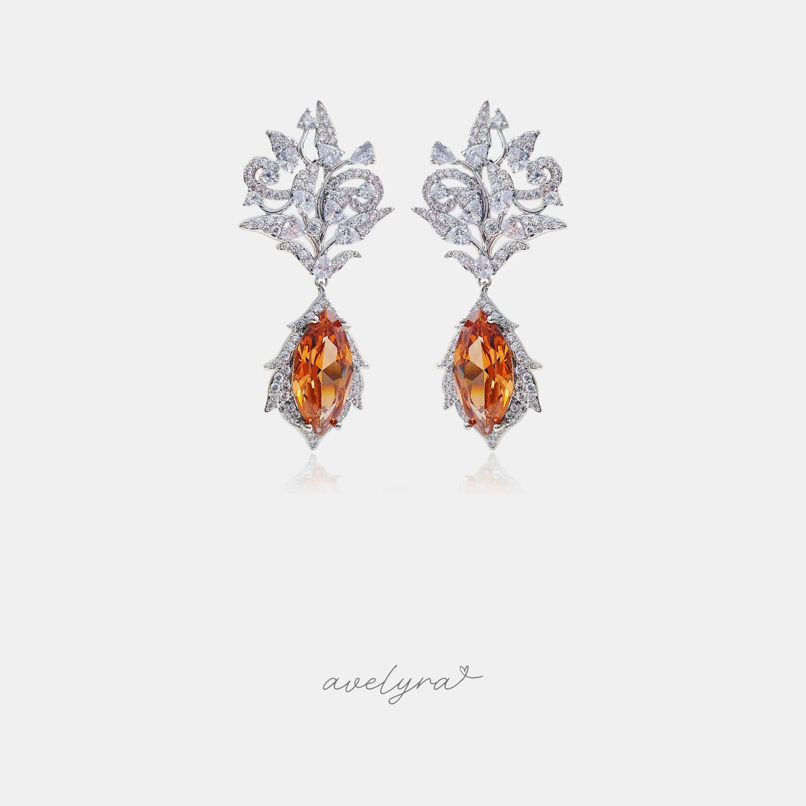 Silver-tone crystal filigree dangle earrings with amber-orange marquise stone drops.