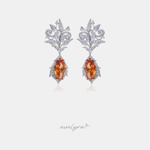 Silver-tone crystal filigree dangle earrings with amber-orange marquise stone drops.