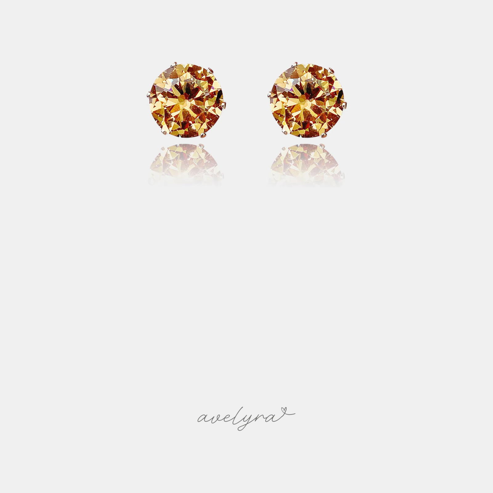 Small stud earrings each set with a single round faceted amber-gold crystal.