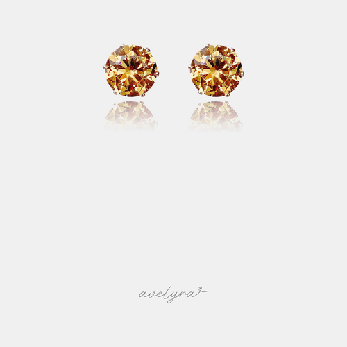 Small stud earrings each set with a single round faceted amber-gold crystal.