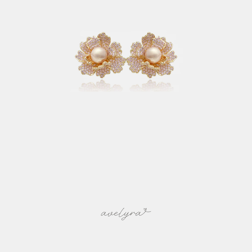 Gold-tone flower stud earrings with pink pave petals surrounding a single cream pearl centre.